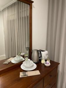uma mesa com dois pratos, uma cafeteira e um espelho em -The Garden Room - with Private Entrance & Private Bathroom em Wentworthville