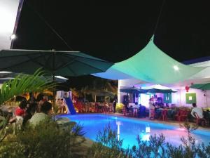 a swimming pool with people sitting under umbrellas at night at Hideaways Restobar and Resort 
