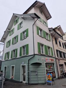 a white and green building with green shutters at Bastis Luxury Studios - Free Parking in Lucerne