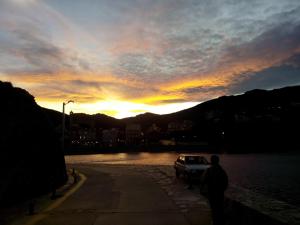 a car parked next to a body of water with a sunset at Hostal Juventus in Portbou