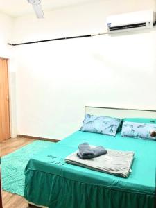 a bed with a green blanket and pillows on it at Isyfaq Homestay 2 bedroom & 2 bathroom in Kota Tinggi