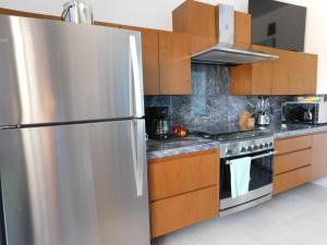 Un refrigerador de acero inoxidable en una cocina con gabinetes de madera. en Oasis Urban Retreat, en Cancún