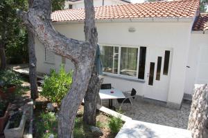 a white house with a table and a tree at Guest House Cattonaro in Šilo
