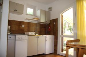 a kitchen with white cabinets and a window at Guest House Cattonaro in Šilo