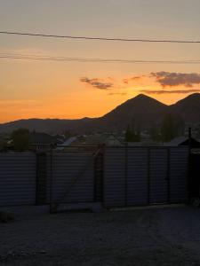 einen Sonnenuntergang hinter einem Zaun mit Bergen im Hintergrund in der Unterkunft Kezgin Guest House in Naryn