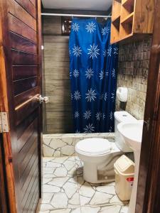 a bathroom with a toilet and a blue shower curtain at Casa Lobos in Lobitos