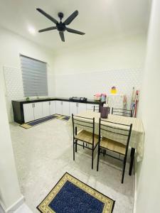 a kitchen with a table and a ceiling fan at Homestay D Twinz (2 unit semi d) in Kuala Berang