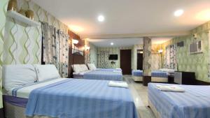 um quarto de hotel com três camas com lençóis azuis em Margie's Place and Coffee Shop Inc. em Mariveles