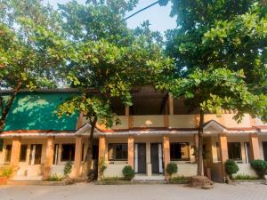 um edifício antigo com árvores em frente em OYO Manori Resort em Manori