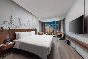 una camera con un grande letto e una TV a schermo piatto di UrCove By Hyatt ShenZhen Bay a Shenzhen