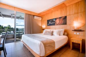 - une chambre avec un grand lit et un balcon dans l'établissement Hôtel Le Lagon, à Nouméa