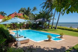 a swimming pool with an umbrella and the ocean at Beachfront Villa Baan Rim Haad 3BR in Lamai