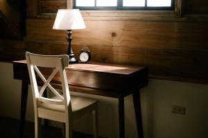 einen Schreibtisch mit einem Stuhl, einer Lampe und einer Uhr in der Unterkunft The Old Country Stone House in Cebu City