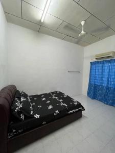a black bed in a room with a blue curtain at Hajjah Homestay Jln Rajawali Tg Agas in Muar