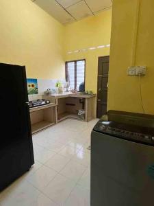 a kitchen with yellow walls and a black refrigerator at Hajjah Homestay Jln Rajawali Tg Agas in Muar