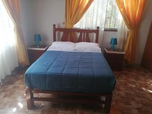 um quarto com uma cama com um cobertor azul em LA FAMILIA NASCA HOUSE em Nazca