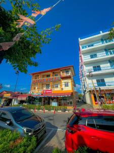 two cars parked in a parking lot in front of a building at Amzar Motel Cenang in Pantai Cenang