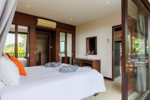 um quarto com 2 camas brancas e uma varanda em Baan Suay Villa em Salad Beach