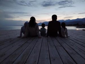 a family sitting on a dock watching the sunset at Bely Parus in Bosteri