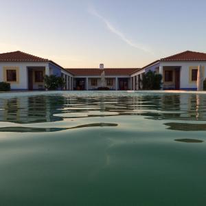 a pool of water in front of some buildings at Refúgio do Monte in Odemira