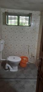 a bathroom with a toilet and a sink and a window at Vacation Rental Home in Kondapalle