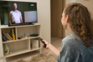 una mujer sosteniendo un control remoto delante de un televisor en Goldcentral Apartment Dob en Budapest