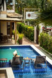 a woman sitting in a chair next to a swimming pool at Hotel Porto Dourado - Rede Bem Bahia in Porto Seguro