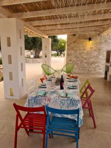 una mesa con sillas rojas y azules en un patio en I trulli di Uma, en Carovigno