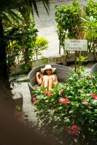 a woman sitting in a wicker chair talking on a cell phone at Hotel Porto Dourado - Rede Bem Bahia in Porto Seguro