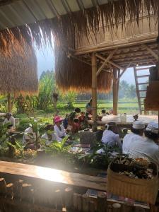 un grupo de personas sentadas alrededor de una mesa en un campo en Lumbung Langit Guest Home, en Gianyar