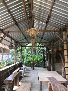 un pabellón de madera con mesas de madera y una lámpara de araña en Lumbung Langit Guest Home, en Gianyar