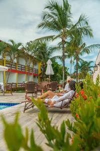 um grupo de pessoas deitadas em toalhas à beira da piscina num resort em Bem Bahia Hotel - Rede Bem Bahia em Porto Seguro