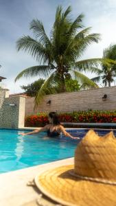 uma mulher numa piscina ao lado de uma palmeira em Bem Bahia Hotel - Rede Bem Bahia em Porto Seguro