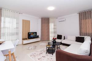 a living room with a white couch and a tv at Stylish City Apartment in Vlorë