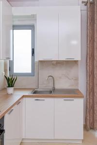 a white kitchen with a sink and a window at Stylish City Apartment in Vlorë