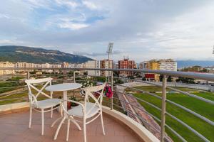 a balcony with two chairs and a table at Stylish City Apartment in Vlorë