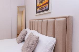 a bedroom with a bed with two pillows and a mirror at Stylish City Apartment in Vlorë
