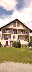 un gran edificio blanco con ventanas y un campo de césped en Vila Puiu Borsa MM en Borşa