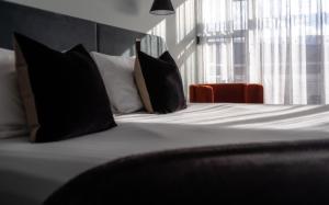 a bed with black and white pillows and a window at Salamanca Suites in Hobart