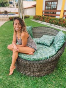 a woman sitting on a wicker couch in the grass at Bem Bahia Hotel - Rede Bem Bahia in Porto Seguro