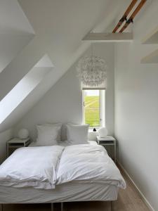 a white bed in a white room with a window at Rum og rooms in Brundby