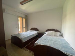 2 łóżka w małym pokoju z oknem w obiekcie 396 Blumar Chalet North Coast Sidi-abdelrahman families & couples only w mieście El Alamein