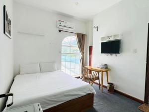 a bedroom with a bed and a desk and a television at Con Son Island Hotel in Con Dao
