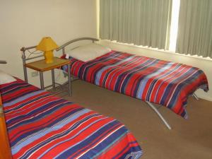 een kamer met 2 bedden en een tafel met een lamp bij 22 Weemilah Drive Pambula Beach in Pambula Beach