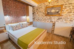 1 dormitorio con cama y pared de ladrillo en Kalderimi Studio, en Sotír