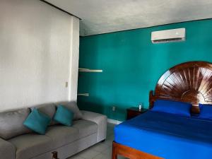 ein Schlafzimmer mit einem Bett und einem Sofa darin in der Unterkunft Casa del Sol in San Pedro Pochutla