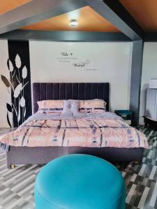 a bedroom with a large bed with a blue stool at Rvenue apartelle in Lucban