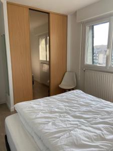 1 dormitorio con cama blanca y ventana en BELLE VUE MER - Villers sur mer, en Villers-sur-Mer