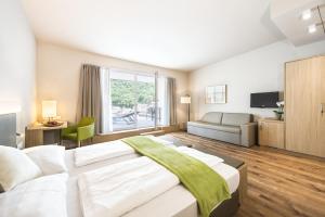 a large bedroom with a large bed and a couch at Hotel CampingPark Steiner in Laives