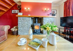 a living room with a fireplace and a table at Beudy Bach in Silian